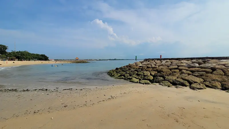 The calm, reef-sheltered shallows and wide sand of Sanur beach in the morning
